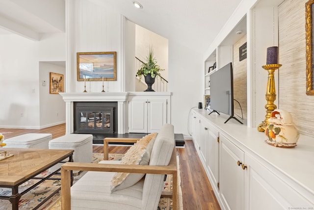 sitting room with vaulted ceiling, built in features, and dark hardwood / wood-style floors