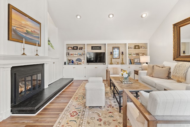 living room featuring built in shelves, light hardwood / wood-style flooring, and lofted ceiling