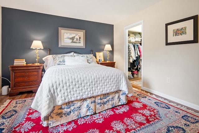 bedroom featuring a spacious closet, a closet, and hardwood / wood-style floors