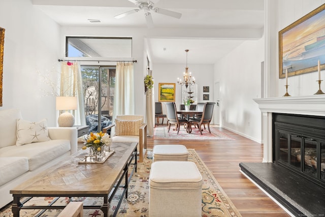 living room with ceiling fan with notable chandelier and hardwood / wood-style flooring