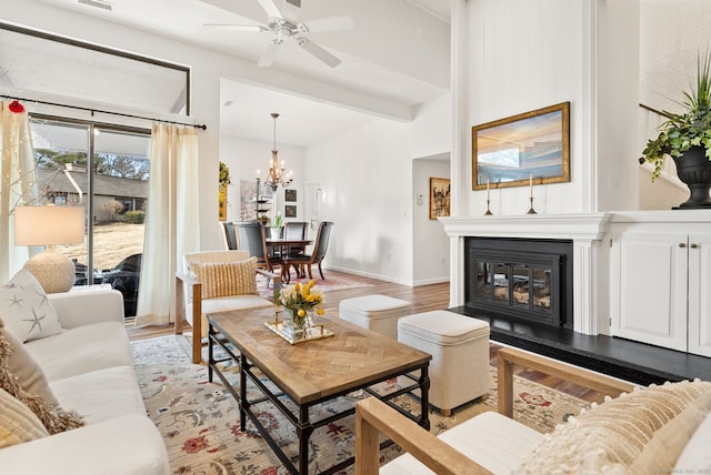 living room with ceiling fan with notable chandelier and light hardwood / wood-style flooring