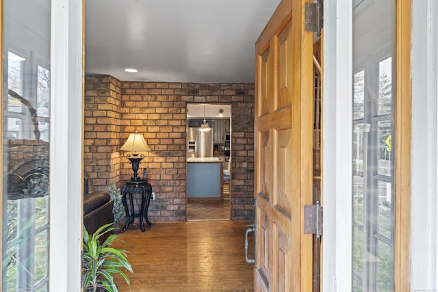 foyer entrance featuring hardwood / wood-style flooring and brick wall