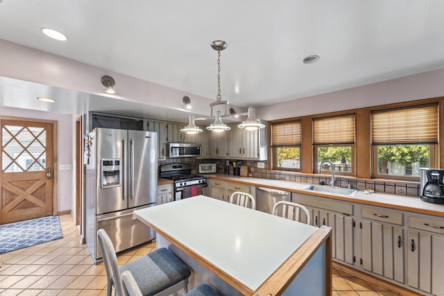 kitchen featuring stainless steel appliances, sink, light tile patterned flooring, a kitchen island, and pendant lighting