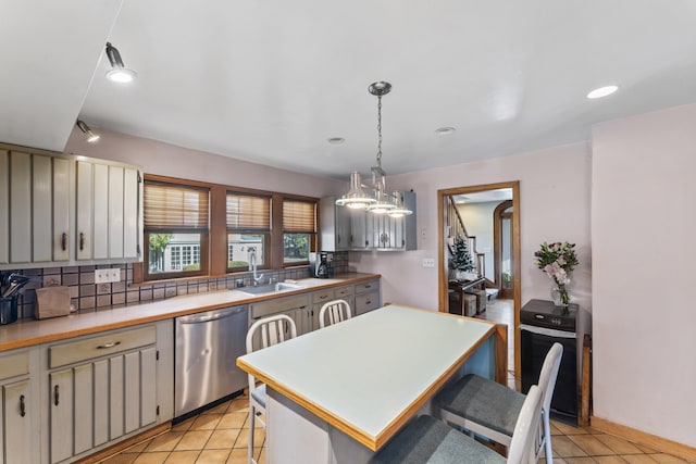 kitchen with sink, a center island, light tile patterned flooring, stainless steel dishwasher, and hanging light fixtures