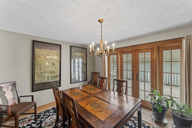 dining area with a textured ceiling, french doors, an inviting chandelier, and hardwood / wood-style flooring