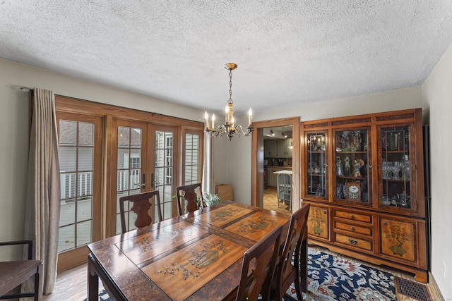 dining area with french doors, an inviting chandelier, and a textured ceiling