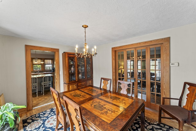 dining room featuring a textured ceiling, french doors, a chandelier, and hardwood / wood-style flooring