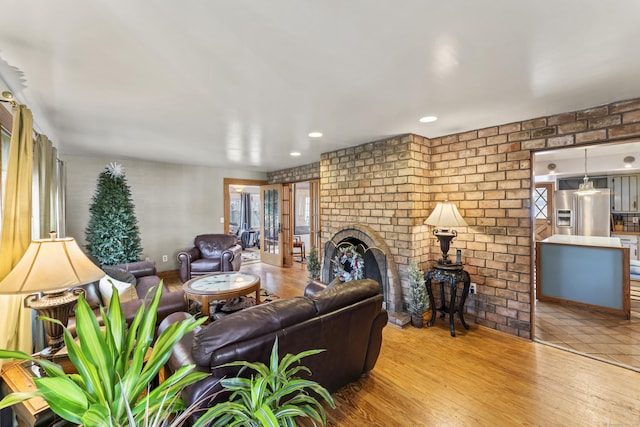 living room featuring brick wall, a brick fireplace, and light hardwood / wood-style flooring