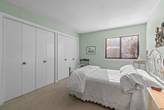 carpeted bedroom featuring two closets and a textured ceiling