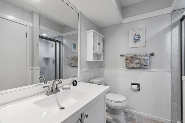 bathroom with vanity, toilet, and a shower with door