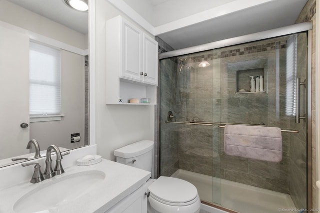 bathroom with an enclosed shower, vanity, and toilet