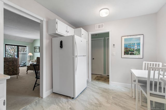 kitchen featuring white cabinets and white fridge