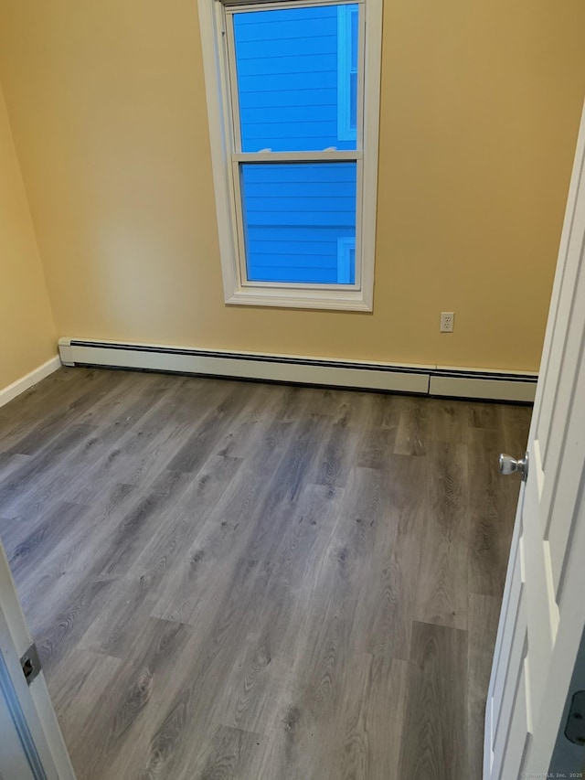 unfurnished room featuring baseboard heating and hardwood / wood-style flooring