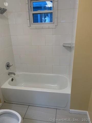 bathroom featuring tiled shower / bath combo, toilet, and tile patterned floors