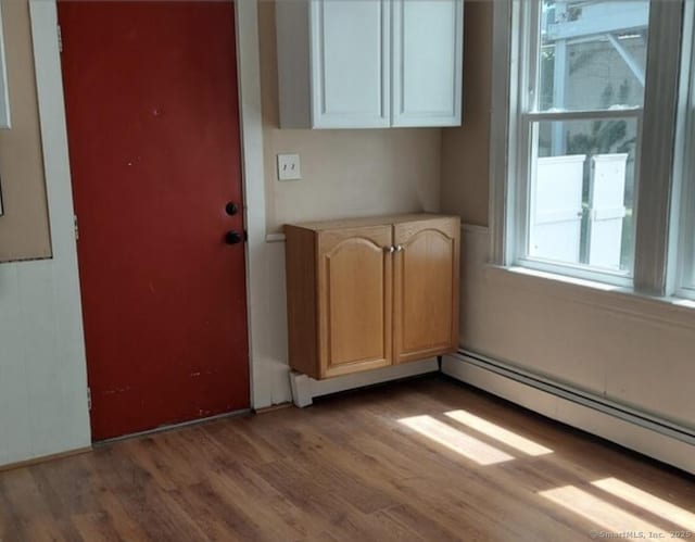 unfurnished dining area featuring a baseboard heating unit and light wood-type flooring