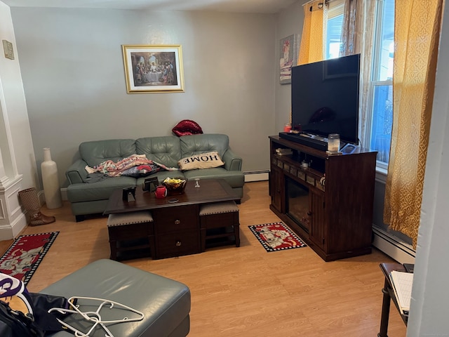 living room with a baseboard heating unit and light wood-type flooring