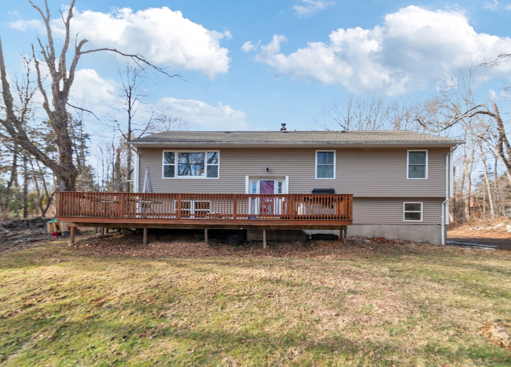 rear view of property with a wooden deck and a lawn