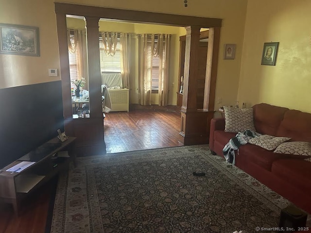 living room with dark hardwood / wood-style flooring and decorative columns