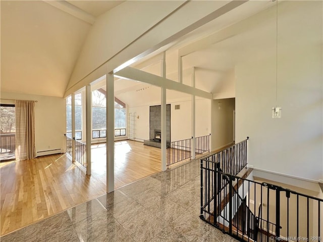 interior space with high vaulted ceiling and a baseboard heating unit