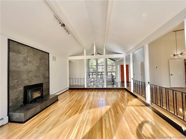 unfurnished living room with a baseboard radiator, hardwood / wood-style floors, lofted ceiling, and rail lighting