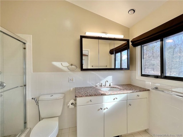 bathroom with an enclosed shower, lofted ceiling, tile patterned floors, vanity, and tile walls