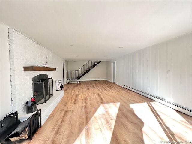 unfurnished living room featuring a baseboard heating unit, a brick fireplace, and light hardwood / wood-style flooring