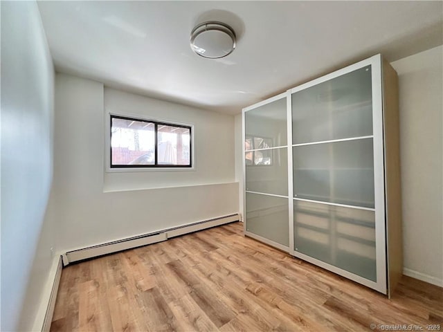 unfurnished bedroom with baseboard heating and light hardwood / wood-style flooring