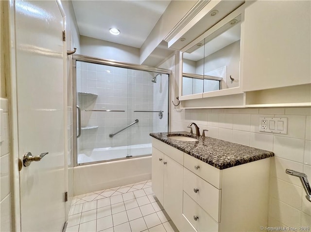 bathroom featuring tile patterned flooring, bath / shower combo with glass door, vanity, and tasteful backsplash