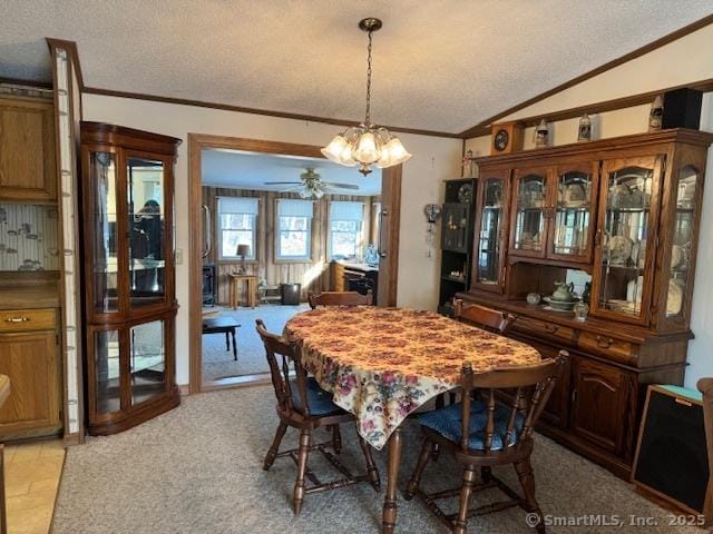 carpeted dining space with lofted ceiling, ornamental molding, a chandelier, and a textured ceiling