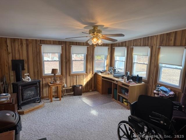 interior space featuring a healthy amount of sunlight, a wood stove, and ceiling fan