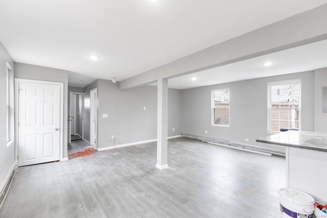 basement featuring light hardwood / wood-style floors and baseboard heating