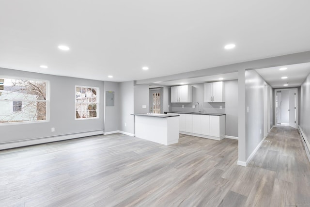 kitchen featuring sink, white cabinets, light hardwood / wood-style flooring, kitchen peninsula, and a baseboard heating unit