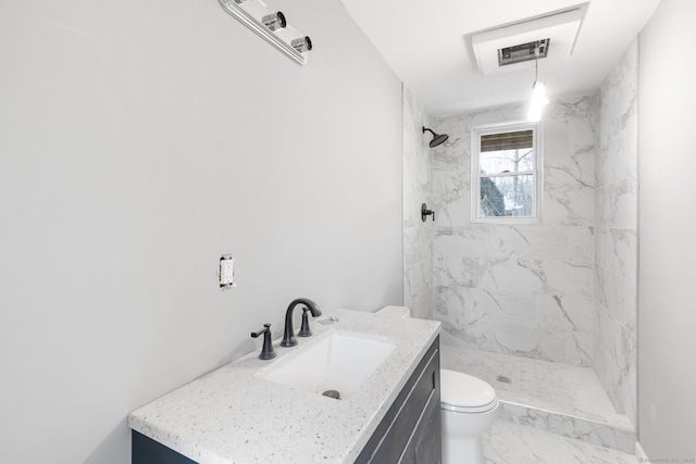 bathroom with tiled shower, vanity, and toilet