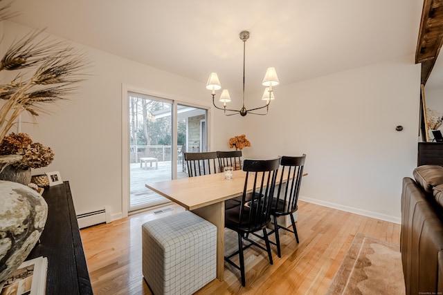 dining space featuring light wood-type flooring, a baseboard heating unit, and a notable chandelier