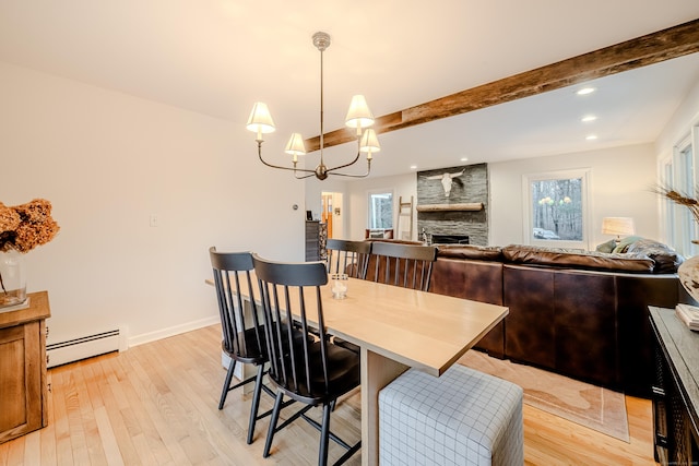 dining area featuring a baseboard heating unit, a stone fireplace, an inviting chandelier, light hardwood / wood-style flooring, and beam ceiling