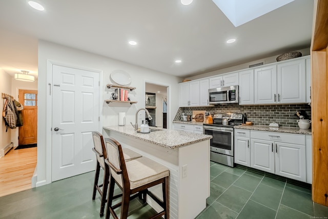 kitchen featuring a breakfast bar, sink, white cabinetry, a skylight, and appliances with stainless steel finishes