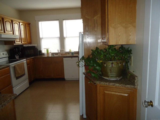 kitchen featuring dark stone counters and white appliances