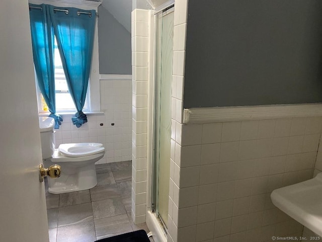 bathroom featuring toilet, tile patterned flooring, tile walls, and walk in shower