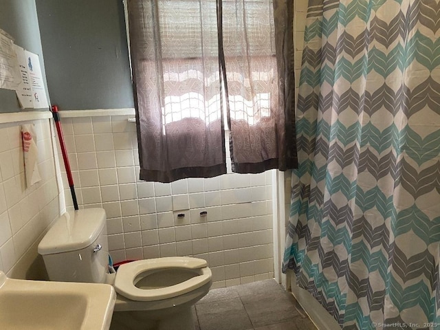 bathroom featuring curtained shower, tile patterned flooring, sink, tile walls, and toilet