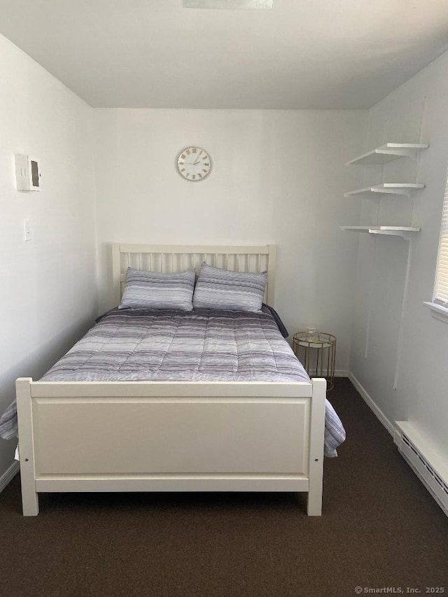 bedroom featuring a baseboard heating unit and dark colored carpet