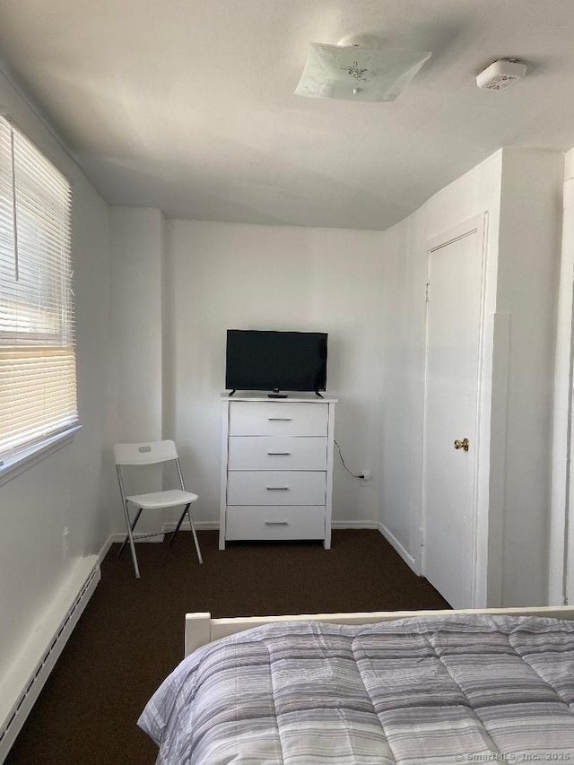 carpeted bedroom with a baseboard heating unit and multiple windows