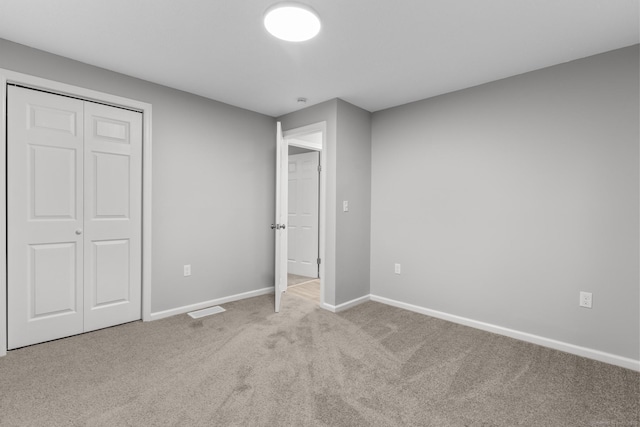 unfurnished bedroom featuring a closet and light colored carpet