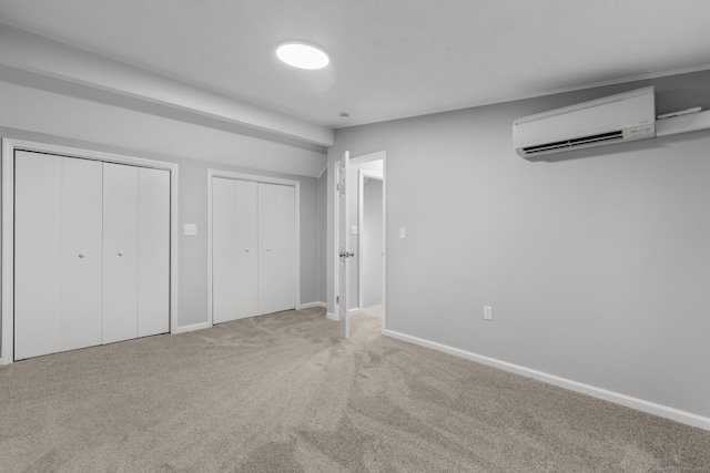 unfurnished bedroom with carpet floors, two closets, and a wall mounted air conditioner