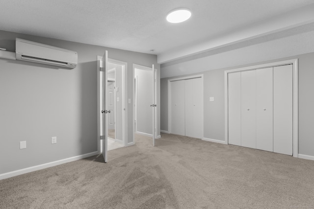 unfurnished bedroom featuring a textured ceiling, two closets, light colored carpet, and a wall mounted air conditioner