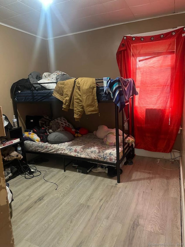 bedroom with ornamental molding and hardwood / wood-style floors