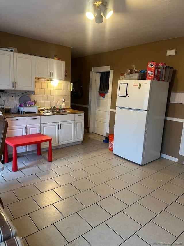 kitchen with white cabinetry, white fridge, sink, and backsplash