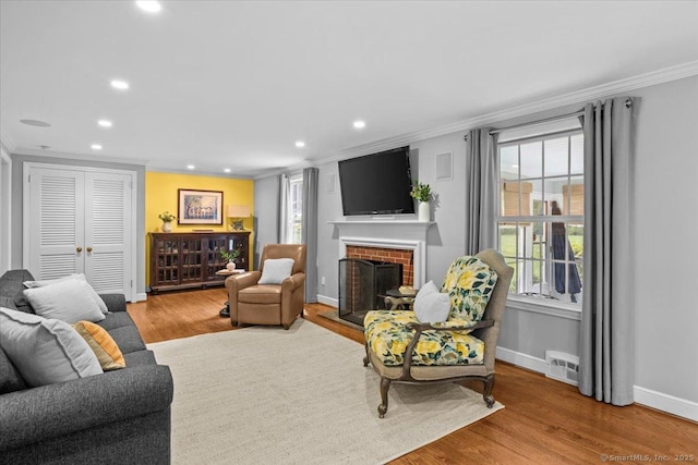 living room with light hardwood / wood-style flooring, crown molding, and a fireplace