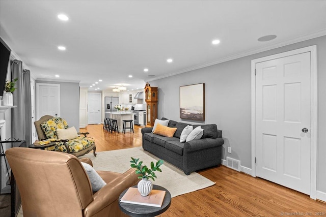 living room with crown molding and light hardwood / wood-style flooring