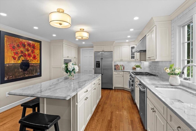 kitchen with a kitchen bar, light stone countertops, premium appliances, and white cabinetry