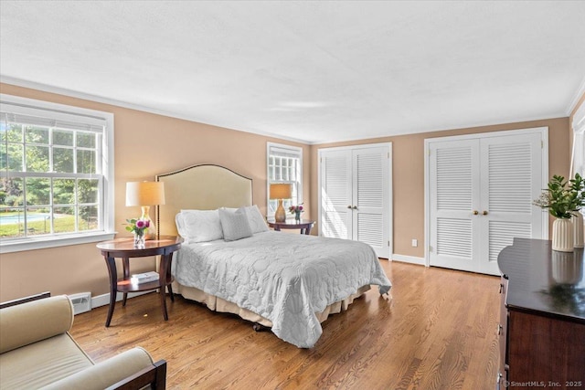 bedroom featuring hardwood / wood-style flooring, two closets, and crown molding